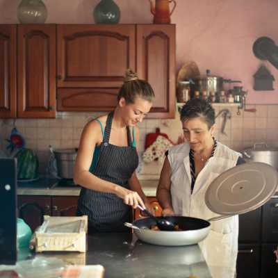 une mamie et sa fille préparent un repas dans une grande poele