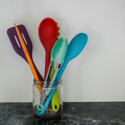 ustensiles de cuisine de toutes les couleurs, posés dans un bocal en verre