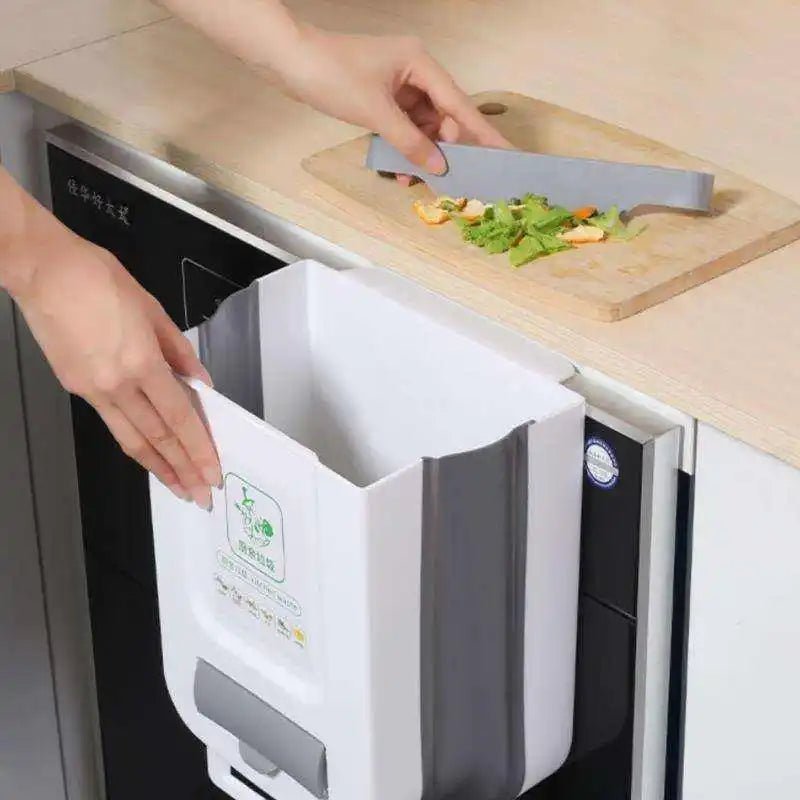 Personne utilisant un vide-presse pour recycler des déchets dans un appareil encastré sous un plan de travail, près d’une planche à découper avec des légumes et un couteau.