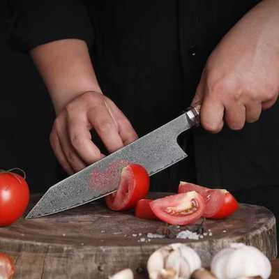 couteau de chef découpant une tomate en quartiers su run billot de bois, avec des gousses d ail en premier plan
