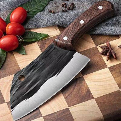 Couteau japonais noir et argenté au manche en bois, posé sur planche à damier avec tomates et épices en arrière-plan. COUTEAU JAPONAIS - COUPERET