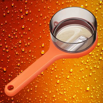 éplucheur à légumes orange sur fond orangé perlé de gouttes d'eau