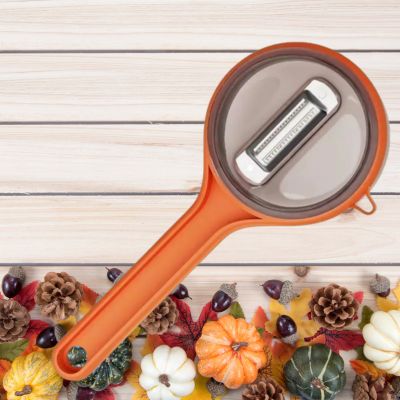 éplucheur à légumes orange posé sur une table à côté de divers légumes