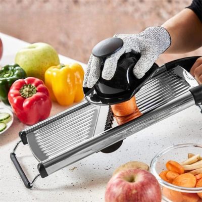 Mandoline cuisine réglable en action, coupe légumes sur plan de travail avec gants de protection, pommes et poivrons autour.