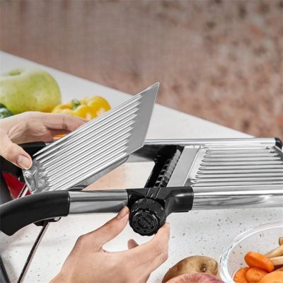 Mandoline cuisine réglable utilisée pour trancher des légumes sur plan de travail, avec lame et guide ajustable.