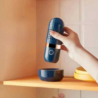 une ain de femme pose un nettoyeur fruits et légumes bleu sur son socle de recharge