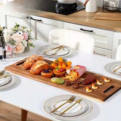 planche à découper en bois XXL sert de plaeau de service pour des crevettes, du pain, des fruits, es rondelles de citron. Le plat est posé au centre d'une belle table bien dressée avec des couverts dorés.