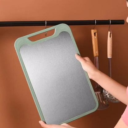 suspension à des crochetsn d'une planche à découper inox  à  côté d'une spatule et d'ue passoire