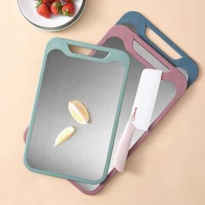 les trois planches à découper inox double face posées sur la table avec un couteau en céramique blanc à côté, et des frases dans une soucoupe