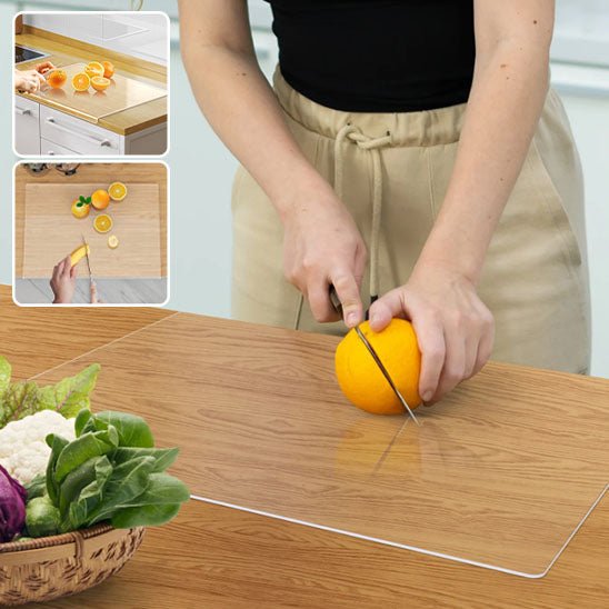 Planche à découper transparente en action: découpe d’orange sur plan de travail avec légumes frais au premier plan.