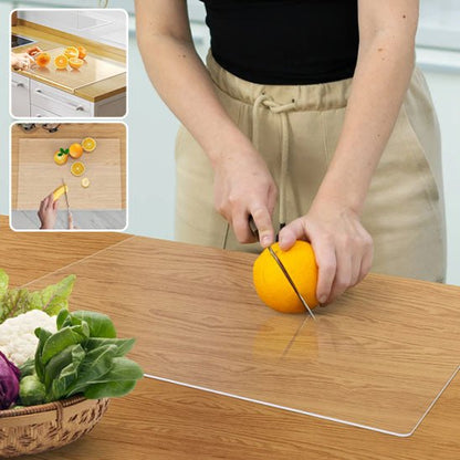 Planche à découper transparente en action: découpe d’orange sur plan de travail avec légumes frais au premier plan.