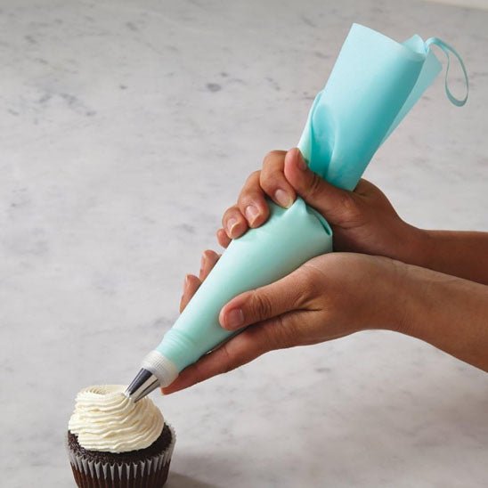 poche à douille dépose de la creme sur un cupcake