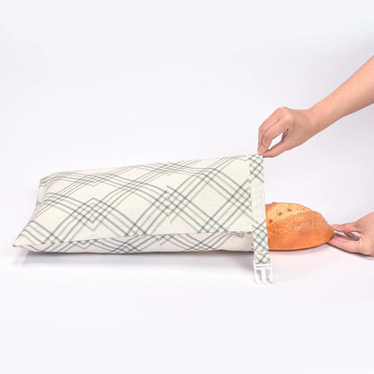 main de femme mettant une baguette dans un sac à pain blanc