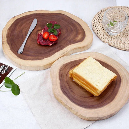 Deux planches à découper rondes en bois naturel avec une tranche de pain et un morceau de viande décoré de tomates et menthe, sur une table.