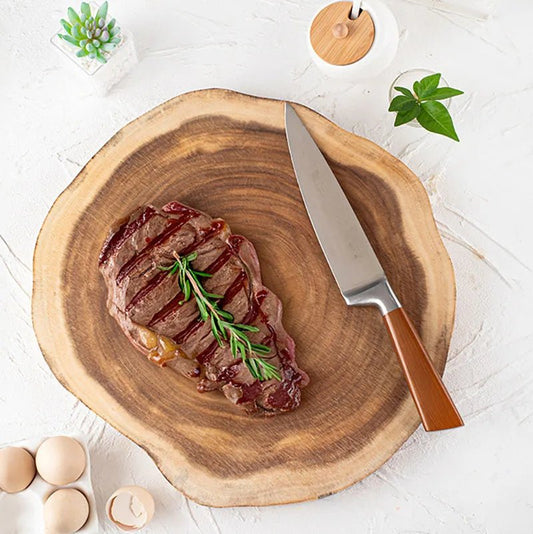 Tranche de steak sur planche à découper en bois avec couteau, romarin frais et œufs à côté, ambiance cuisine naturelle.