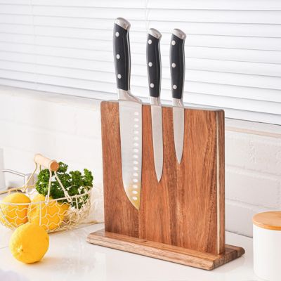 Porte-couteaux magnétique en acacia avec bloc de rangement en bois et couteaux en acier noir à manches noirs, sur plan de travail.